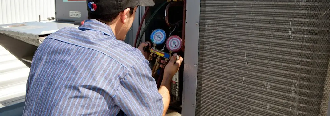 HVAC technician servicing a condenser unit in Ivins