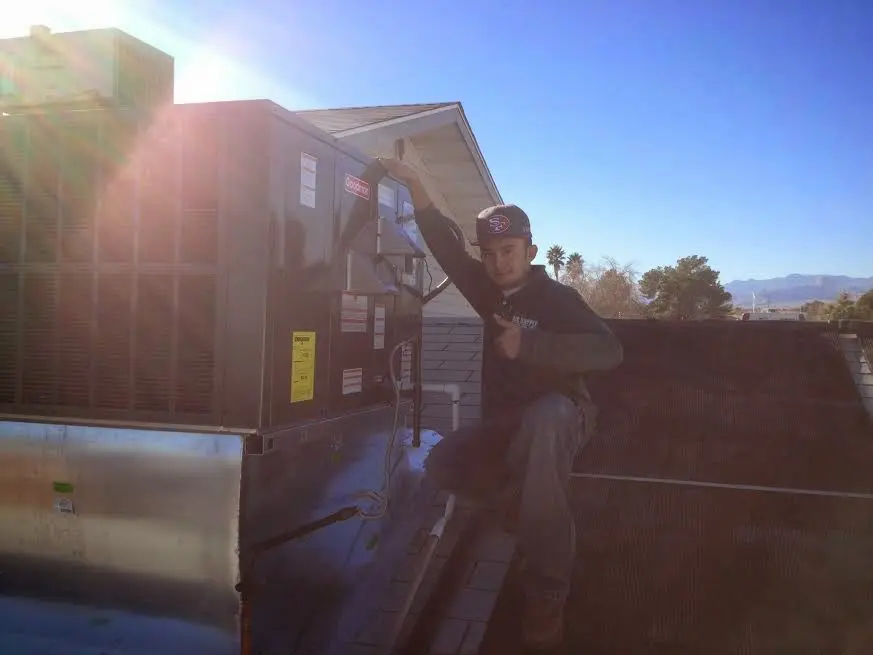 HVAC technician performing AC Tune-Up on a rooftop unit in Ivins